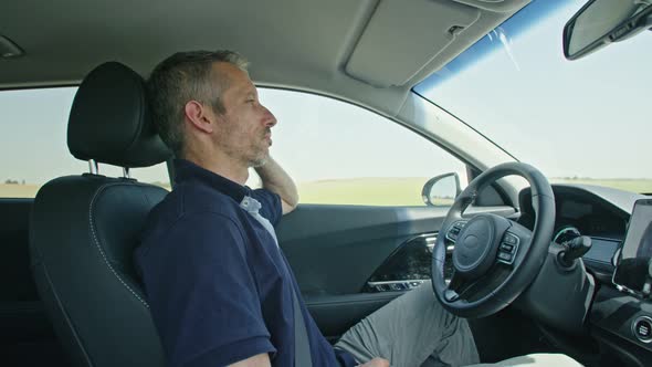 Male driver sitting in an autonomous car, letting the car drive by itself