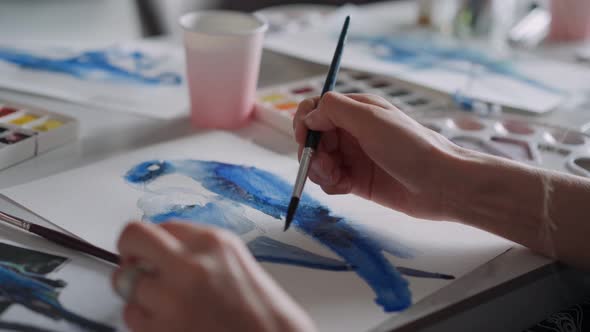 Closeup of a Female Hands Drawing a Parrot on a Sheet of Paper in Different Colors