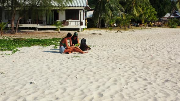 Beautiful ladies enjoying life on paradise island beach break by shallow water with white sand backg