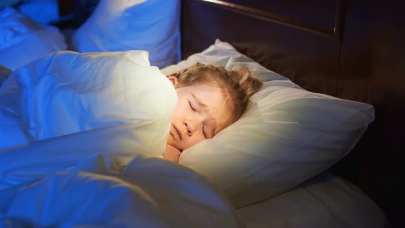 A Little Girl Naps in Bed Sees a Nightmare and Covers Face with a Blanket