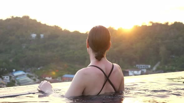 Girl in Swimsuit Walks To Hotel Swimming Pool Edge at Sunset