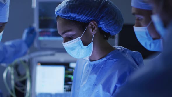 Mixed race surgeons wearing protective clothing discussing in operating theatre