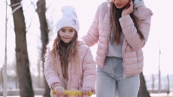 The Mother and Cute Daughter Are Walking in the Park