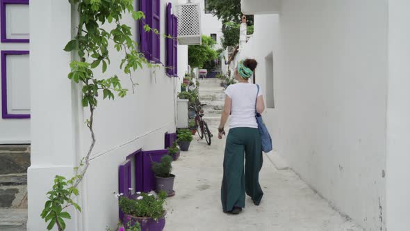 A woman walkin in a purple windowed narrow whitewashed street