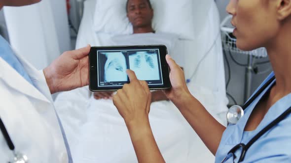 Close-up of multi-ethnic doctors discussing x-ray report on digital tablet in ward at hospital