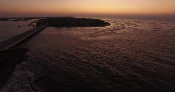 Aerial of ocean waves on island beach at sunrise