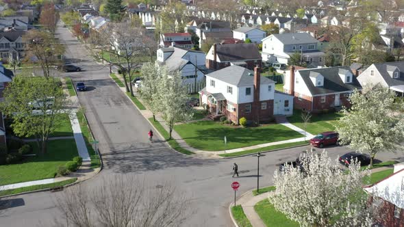 An aerial shot over a suburban neighborhood on a sunny day. The camera, looking down dolly in over t