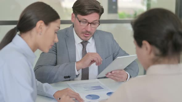 Male and Female Businessperson using Tablet While Preparing Reports