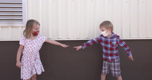 Two little kids in masks touching fingers.