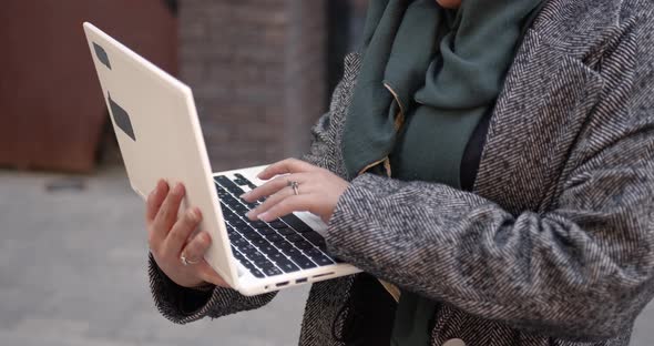 Muslim Woman Using Laptop Standing Outside