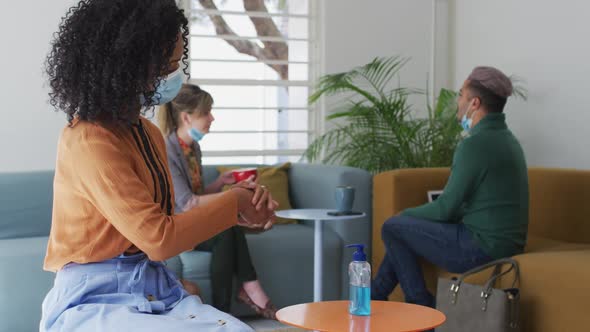 Woman wearing face mask sanitizing her hands at office