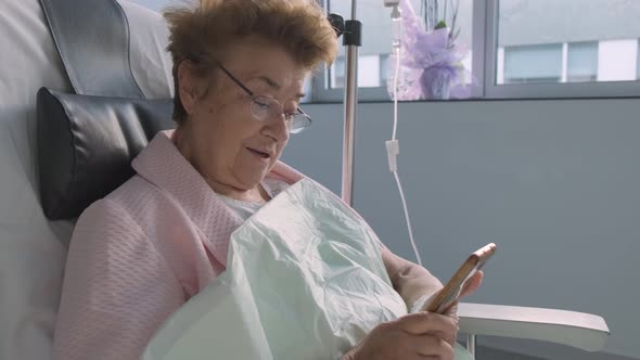 Hospital room, Close up Elderly woman holding mobile phone, intravenous drip Medication