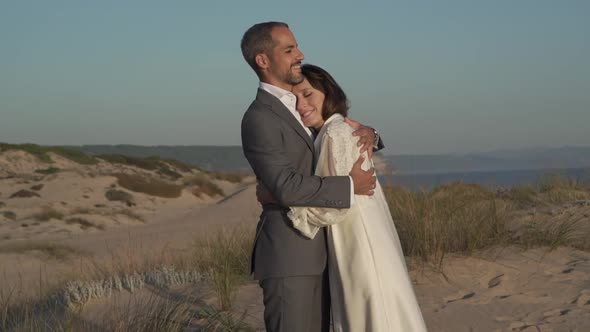 Newlywed couple embracing at seaside