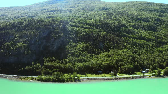 Thicket Mountain Forest At The Coastal Road With Cars Driving On Summertime In Vagavatnet Lake, Norw