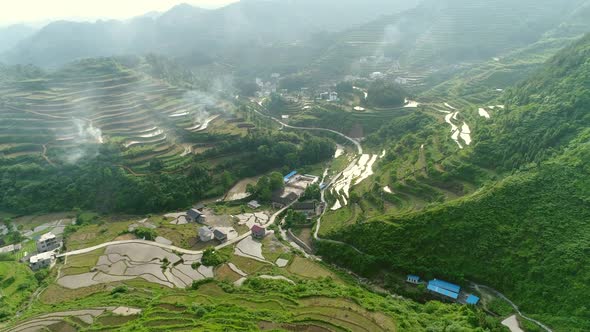 Aerial View of Rural Village Surrounded By Green Terraced Rice Field Farms in South of China