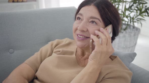 Close-up Face of Happy Brown-eyed Caucasian Woman Talking on the Phone. Portrait of Charming Senior