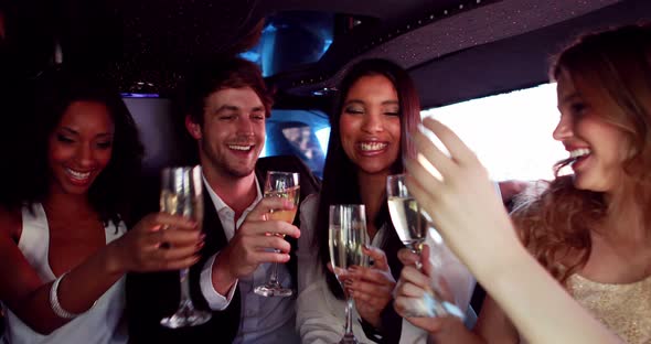 Happy friends drinking champagne in limousine