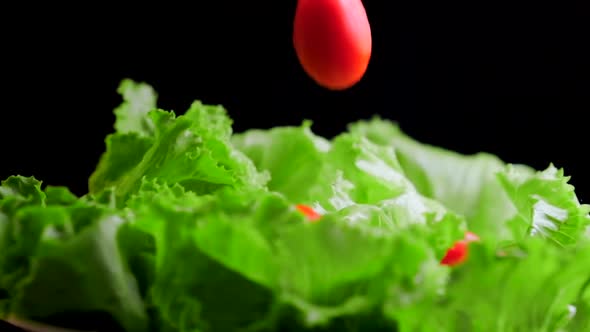 Cherry tomatoes falling on lettuce leaves