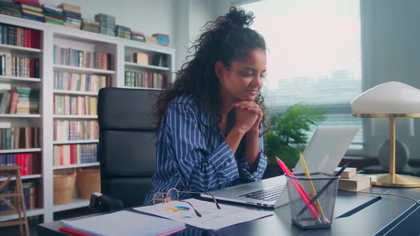 Focused Indian Woman Distracts From Laptop During Work and Turns to Camera