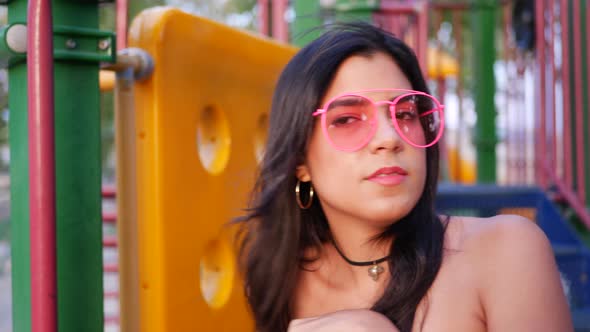 A young hispanic woman hipster wearing vintage fashion clothing and retro pink aviator sunglasses in