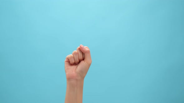 Close up of woman hand showing fist on the blue background.