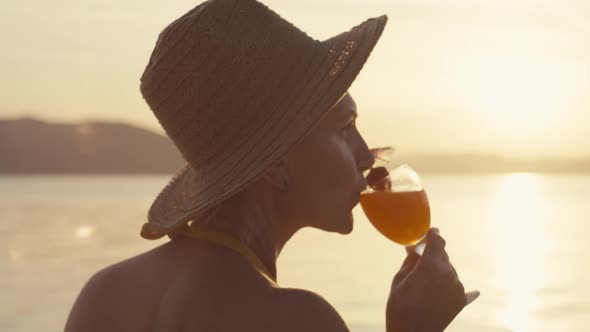 Closeup Video of a Woman Drinking a Cocktail on the Beach During Sunset