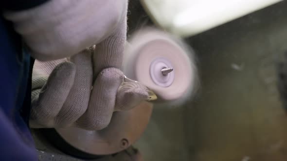 Close Up at the Worker Burnishing the Finished Silver Spoon with a Machinetool at the Plant for