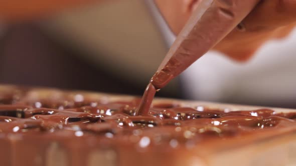 Chocolatier squeezing chocolate into praline mold, handmade fine chocolate praline production, close