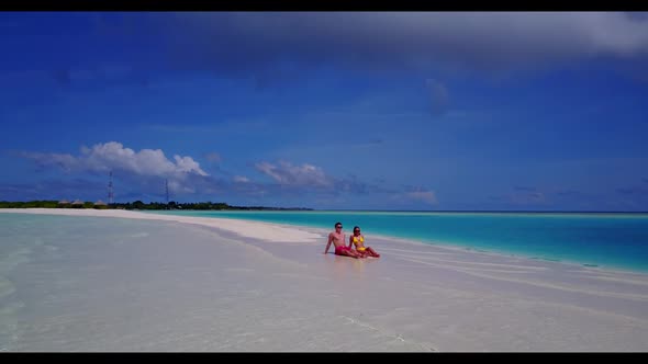 Young couple sunbathing on tranquil tourist beach holiday by transparent ocean and white sandy backg