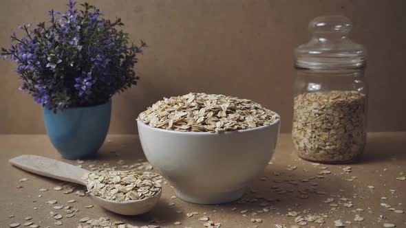 Slow motion of oatmeal falling into a wooden bowl. Whole grain cereals