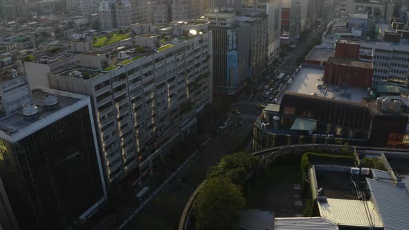 A drone shot of Taipei during sunset panning to the street where you see cars and taxis driving
