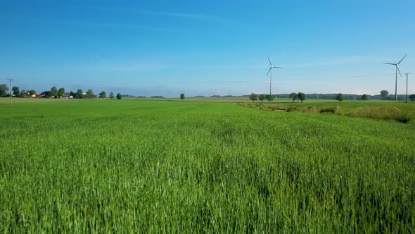 Green Fields With Wind Turbines In Background - aerial pullback