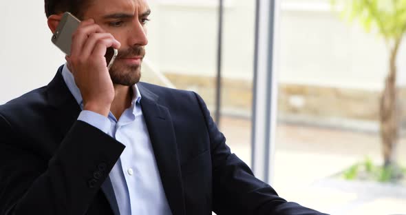 Businessman talking on mobile phone at desk 4k