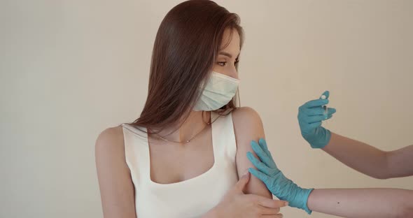Girl in a Mask Getting Injection on Beige Background