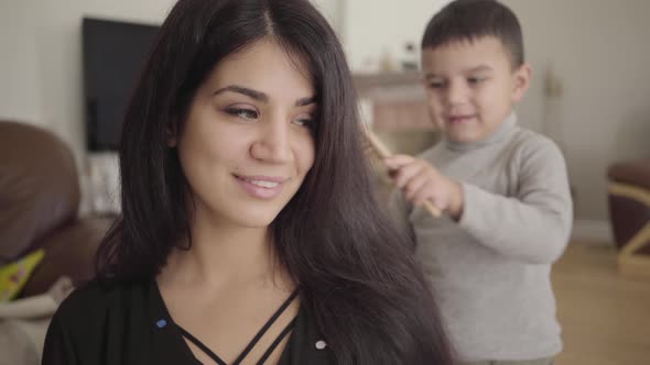 Portrait of a Middle Eastern Hazel-eyed Woman Combed By the Smiling Little Boy
