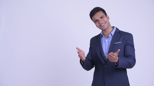 Happy Young Indian Businessman Showing Something and Giving Thumbs Up