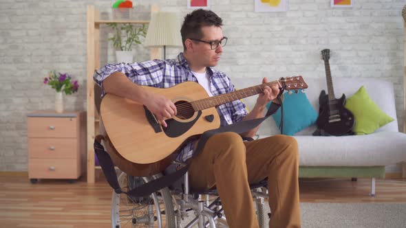 Young Man Disabled Musician in a Wheelchair Playing Guitar