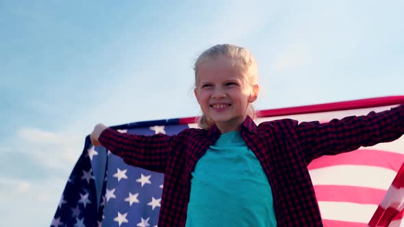 Blonde Girl Waving National USA Flag Outdoors Over Blue Sky at Summer American Flag Country