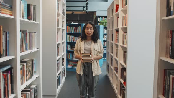 Portrait of Asian Student with Pile of Books in Library