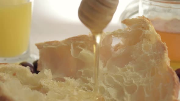 Drizzling honey on fresh baked croissant close up shot