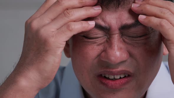 Asian old man with migraine headache.