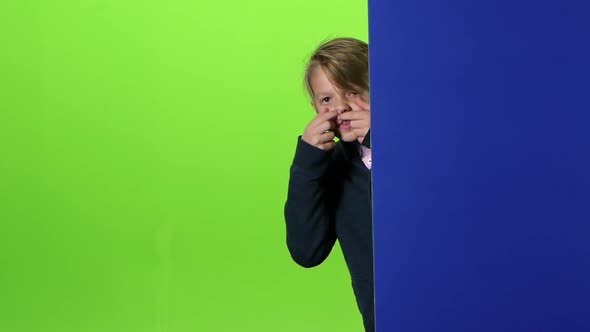 Teenager Peeks Out From Behind and Board Curves of the Face on a Green Screen. Slow Motion