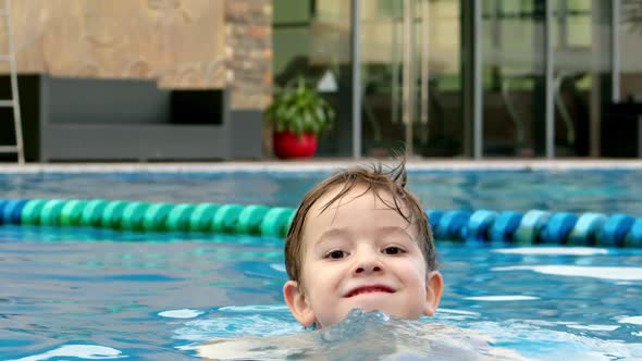 Cheerful Little Boy in Goggles Bathing in the Pool