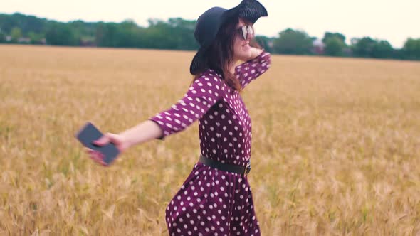 Beautiful Young Woman Walks in a Wheat Field