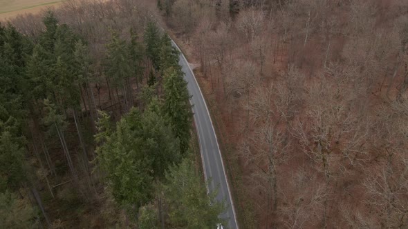 Bird's eye view of a car travelling along a curved countryside highway through a mixed and partially