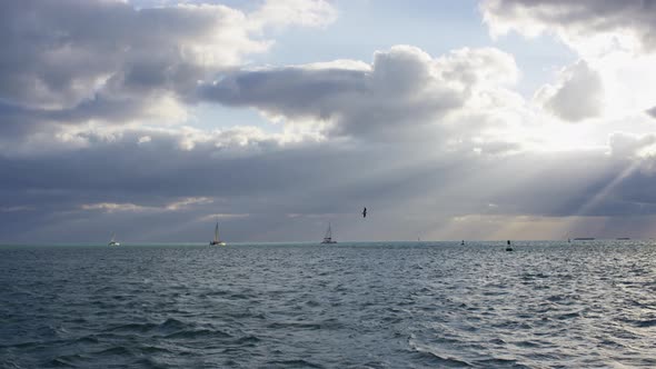 Ocean with sailboats on a cloudy evening alt
