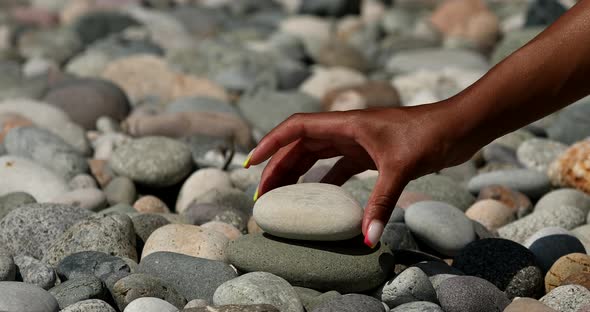 Woman making pyramid of stones.