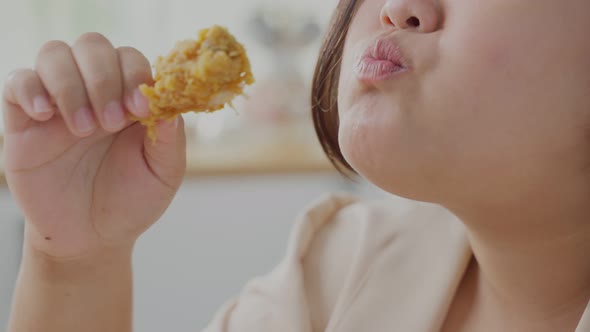 Close up of oversize big women bite fired chicken full mouth enjoy unhealthy food in kitchen at home