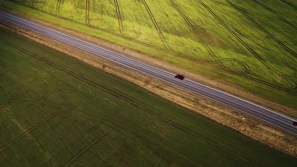 Top View of a Cars Driving Along a Rural Road Between Two Fields