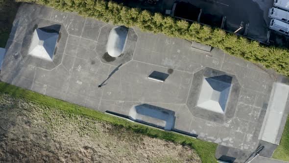 Rotating aerial view of a lone skater at an empty skatepark.